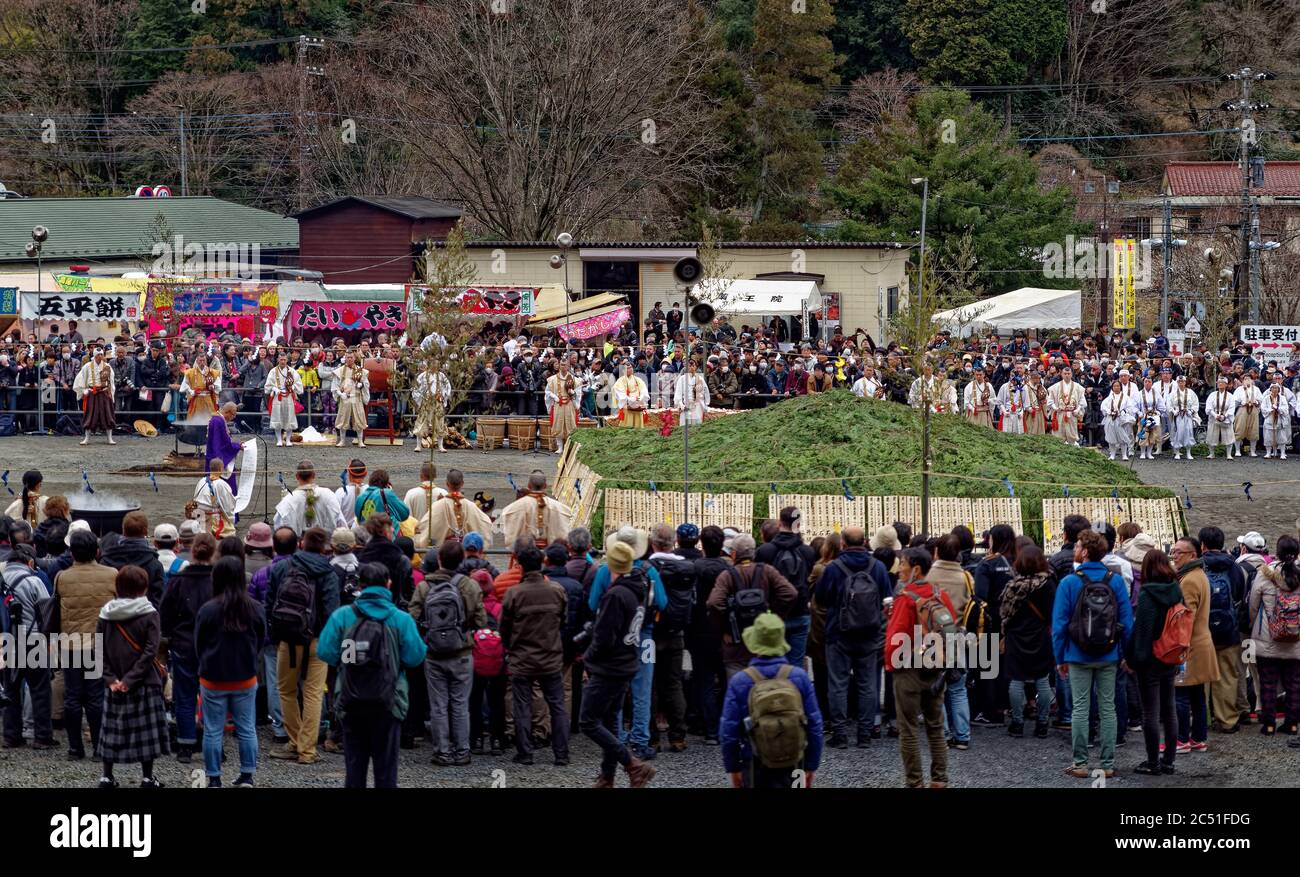 Une grande foule regarde un moine âgé lire et chanter à voix haute d'un long défilement de papier au festival annuel de marche-feu près du Mont Takao, Tokyo Banque D'Images