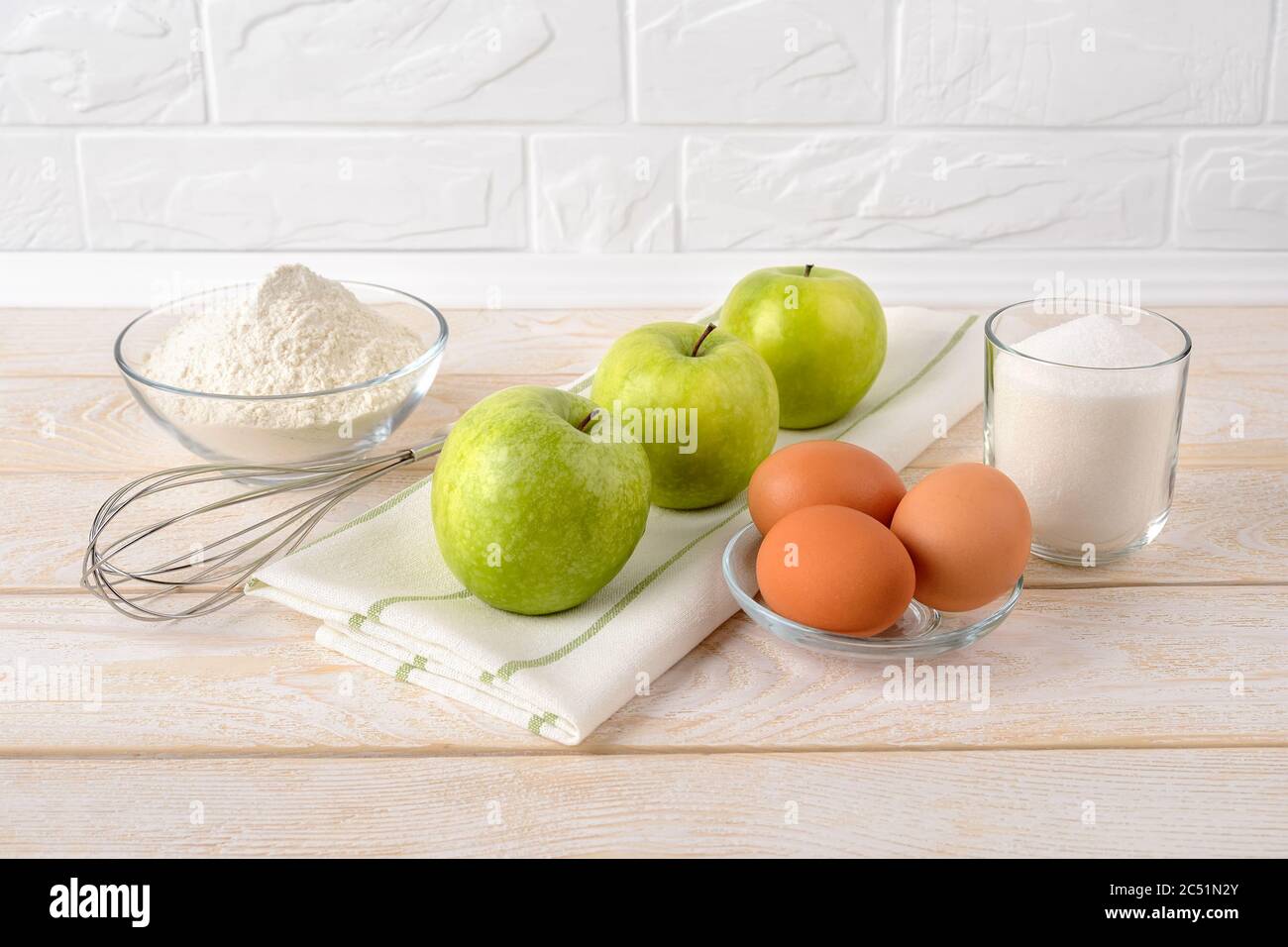 Ingrédients crus pour la tarte aux pommes : pommes vertes aigre, farine de blé, sucre et œufs sur table en bois blanc. Recette pour pâtisseries maison au petit déjeuner Banque D'Images