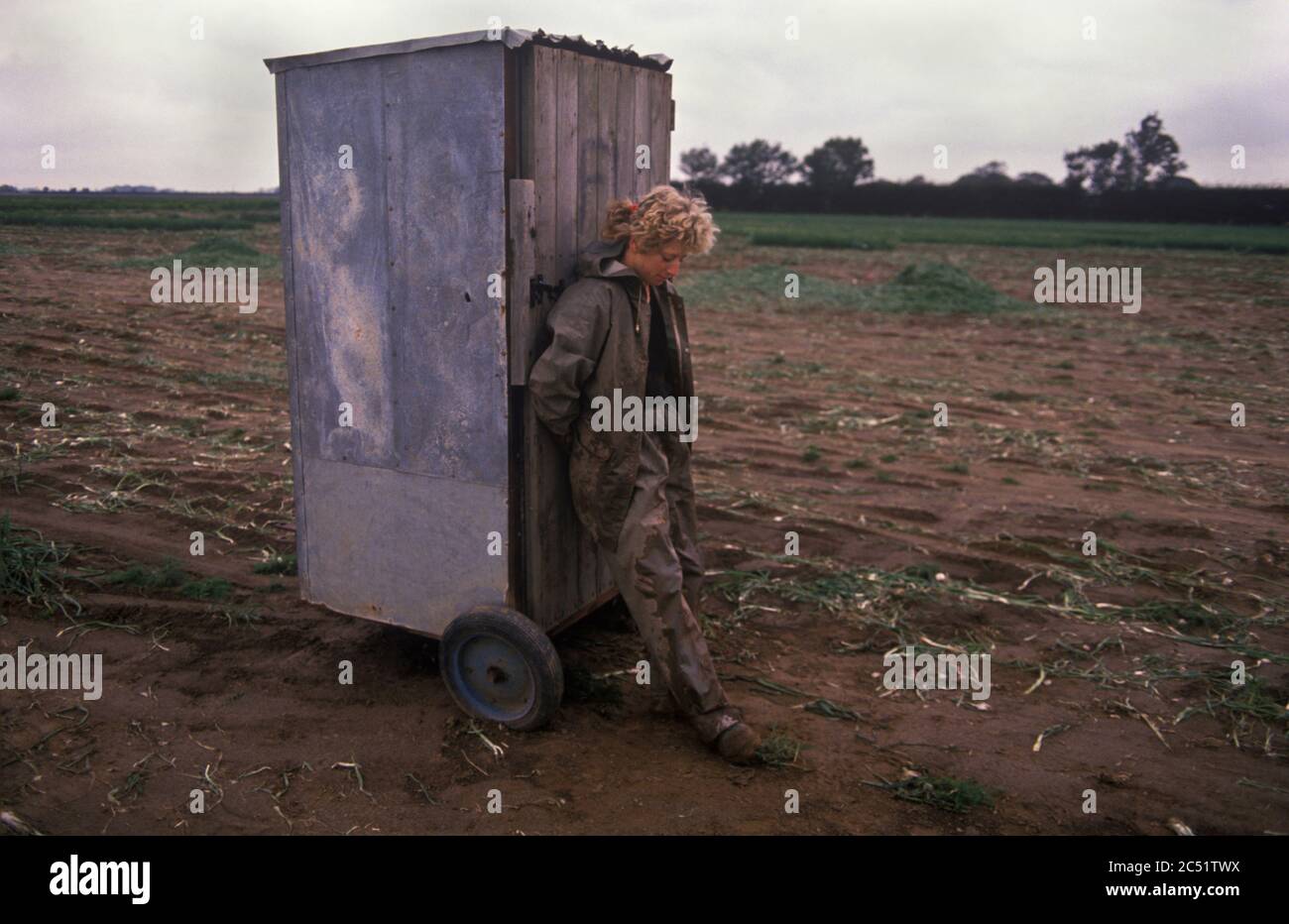 Travail agricole rural à temps partiel faiblement rémunéré The Lincolnshire Fens, East Anglia. 1980s Royaume-Uni. C'est la cabine des toilettes un WC portable, son amie est à l'intérieur et elle garde la porte car il n'y a pas de serrure. HOMER SYKES Banque D'Images
