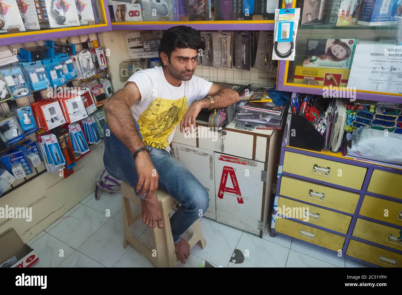 Le vendeur dans un magasin de téléphones mobiles et d'accessoires à Mumbai, en Inde, attend les clients, frappant une position presque Bollywood star de cinéma Banque D'Images