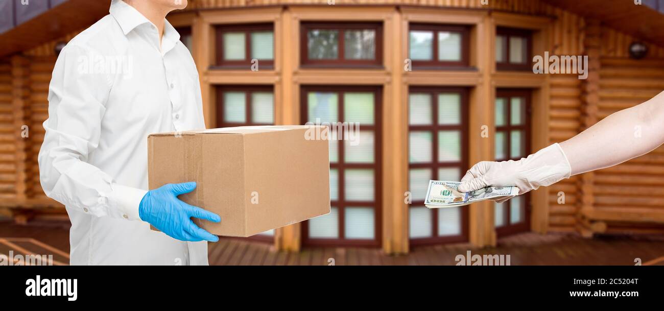 le livreur tient les mains dans des gants stériles de boîte en carton de messagerie et la main tient l'argent pour payer la livraison de nourriture pendant la quarantaine de distance sociale pa Banque D'Images