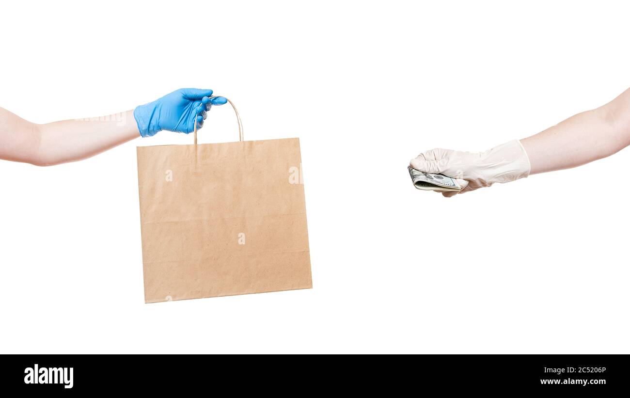 Un emballage écologique en papier marron tient la main d'un liveur dans un gant stérile et la main retient l'argent pour payer pour la livraison de nourriture isoler Banque D'Images