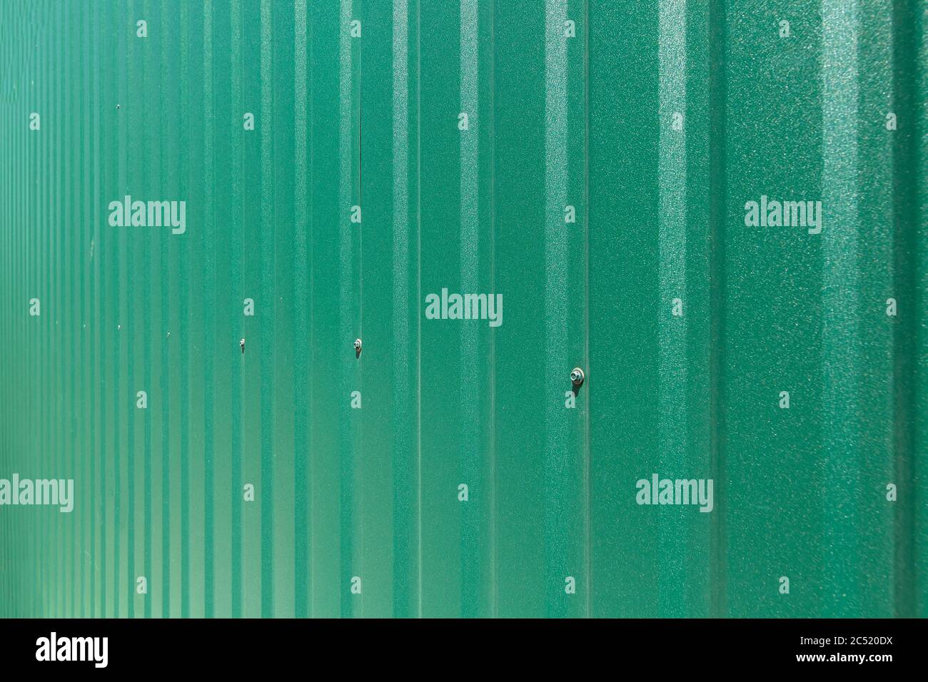 clôture en fer galvanisé avec bandes verticales ondulées clôture de texture de couverture verte de feuille de couleur verte vue latérale, personne. Banque D'Images