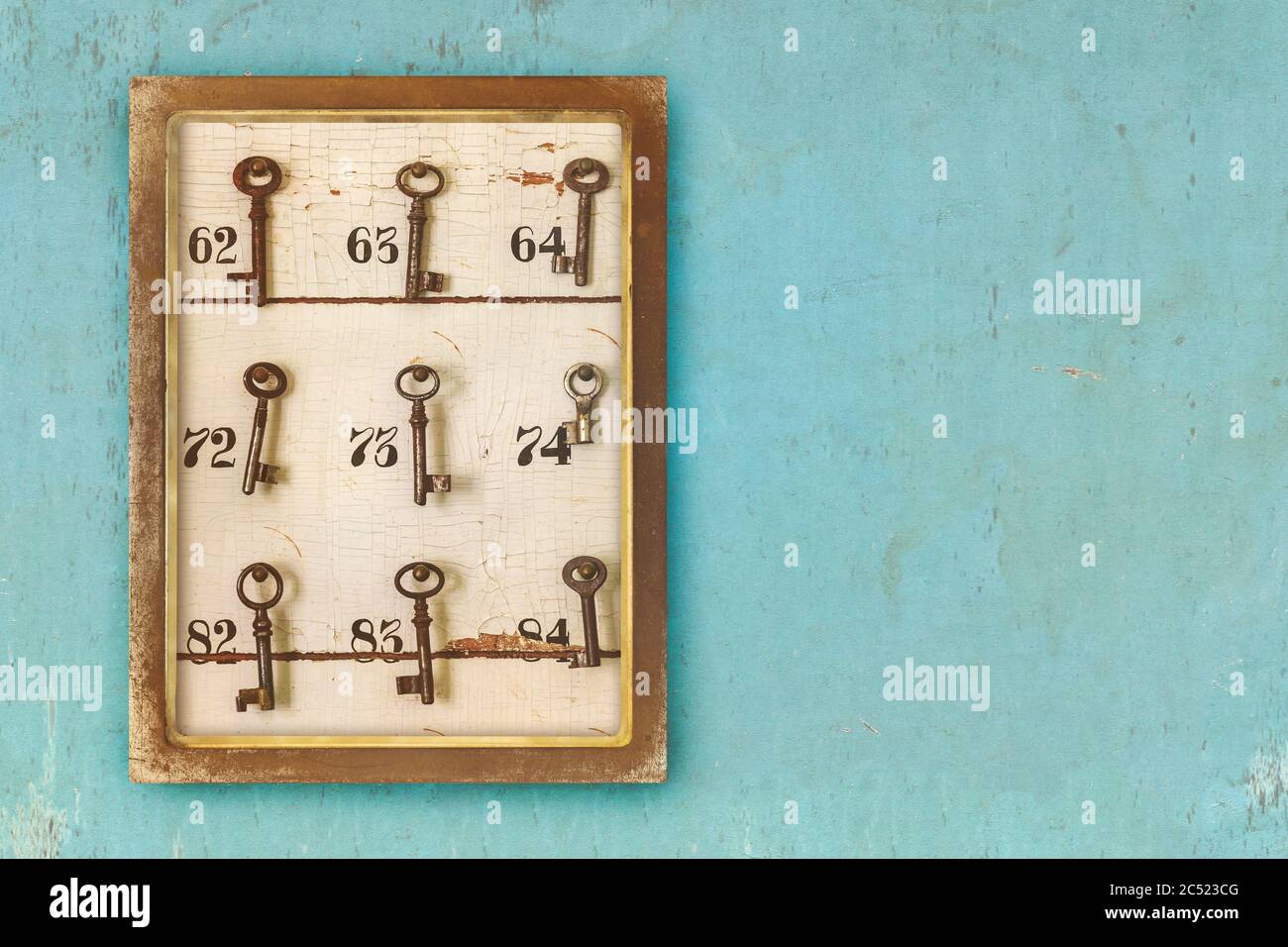 Petit cabinet vintage avec clés d'hôtel rouillées et numéros de chambre sur fond bleu érodé Banque D'Images