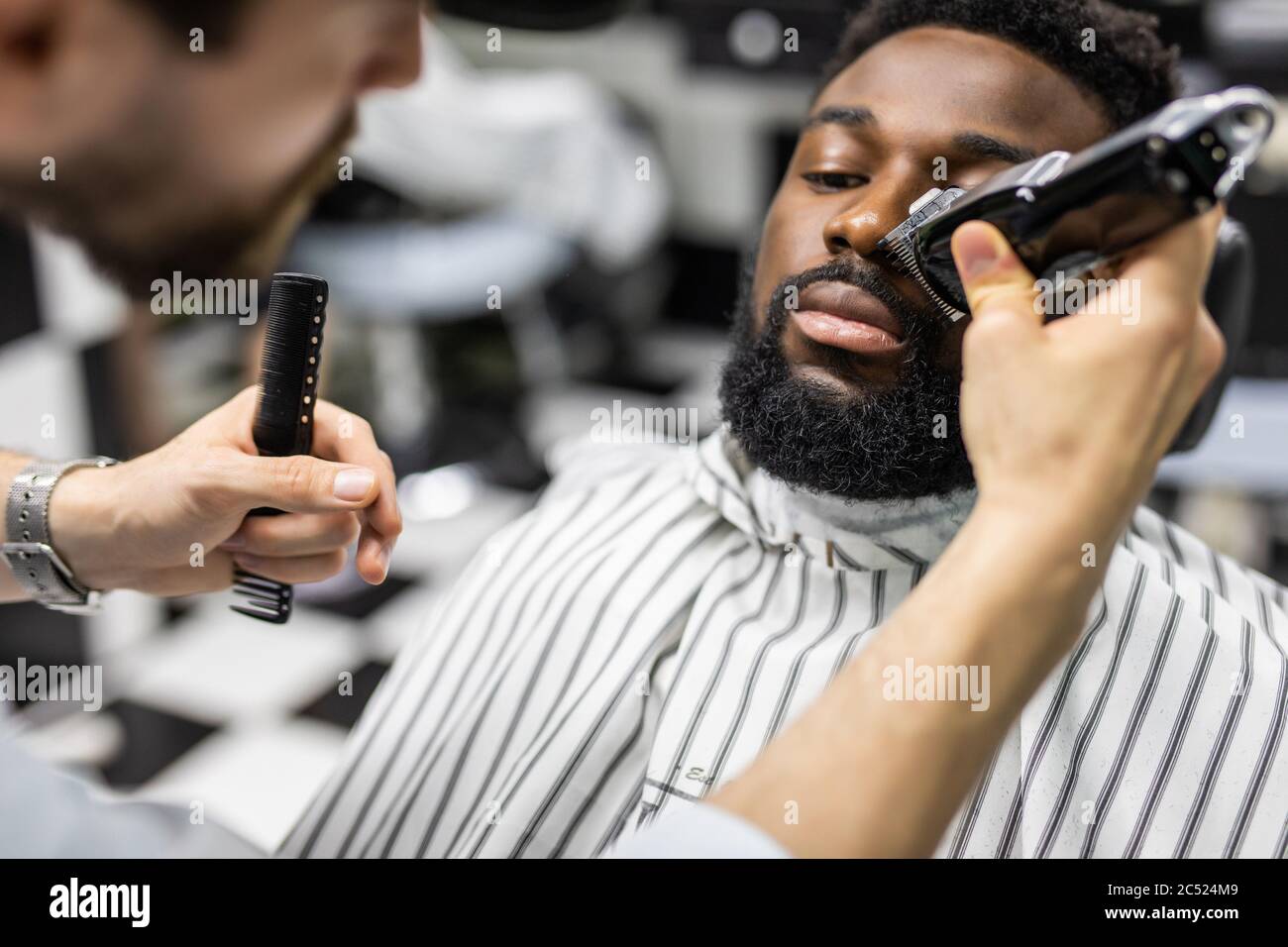 Coiffeur tondeuse cheveux sur jeune homme noir non rasé en atelier de  barbershop.coiffeur professionnel coupe cheveux avec machine à haver  électrique sur l'Afrique Photo Stock - Alamy