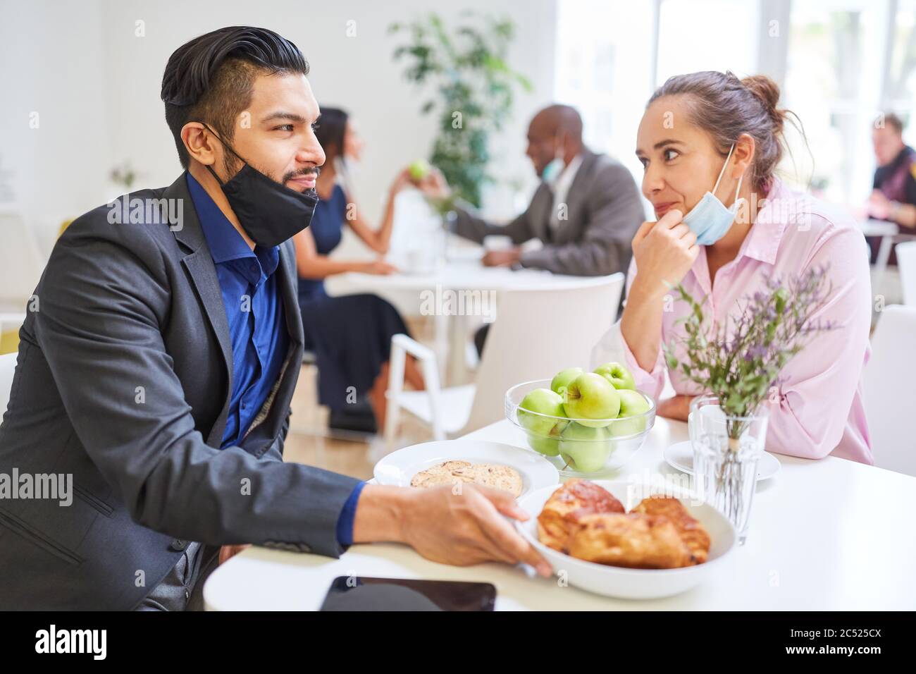 Deux jeunes hommes d'affaires en tant que couple flirtant dans la cafétéria avec un masque facial sur leur menton Banque D'Images