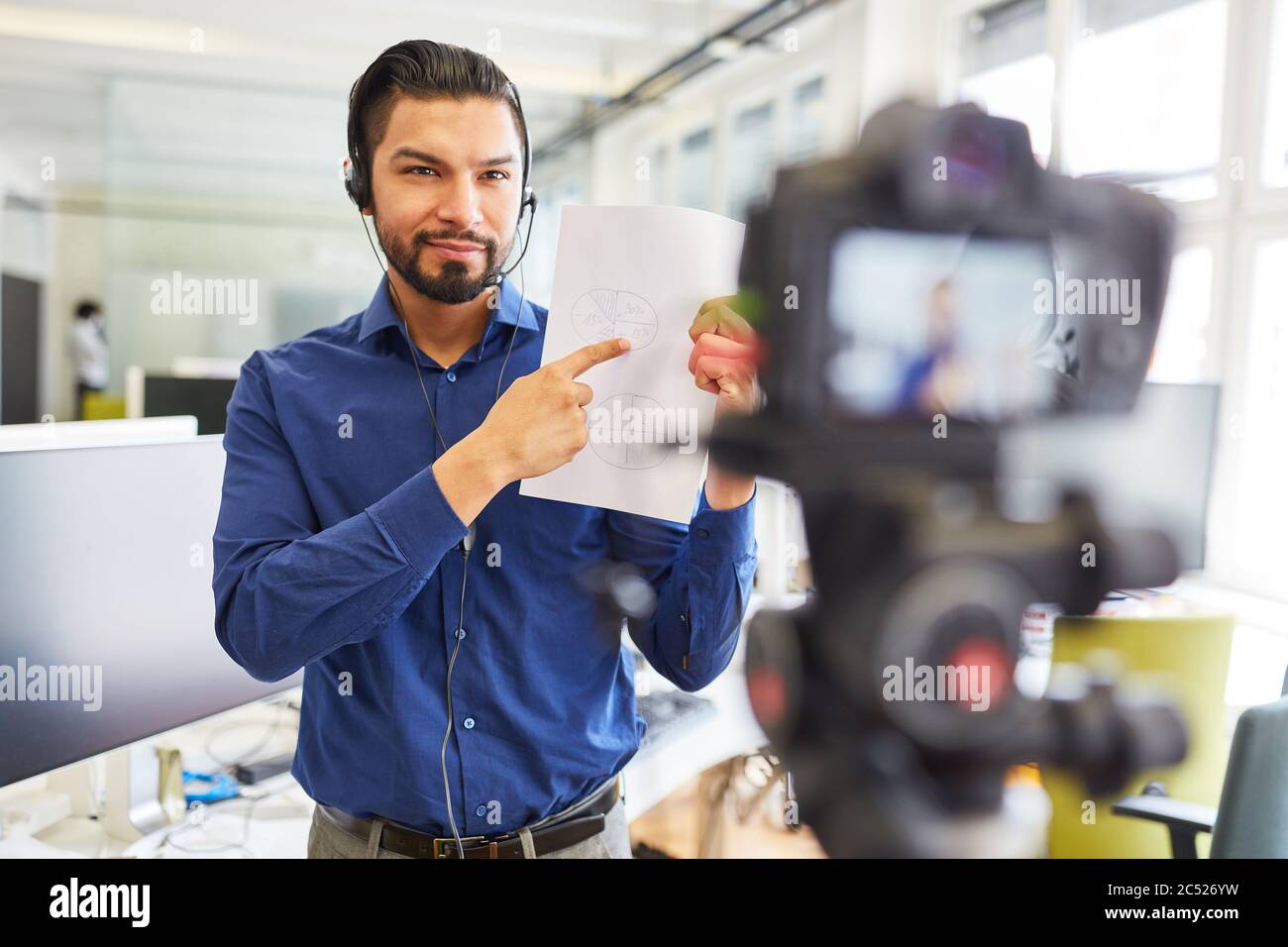 Homme d'affaires avec casque et enregistrement de documents vidéo d'instruction pour un atelier en ligne Banque D'Images