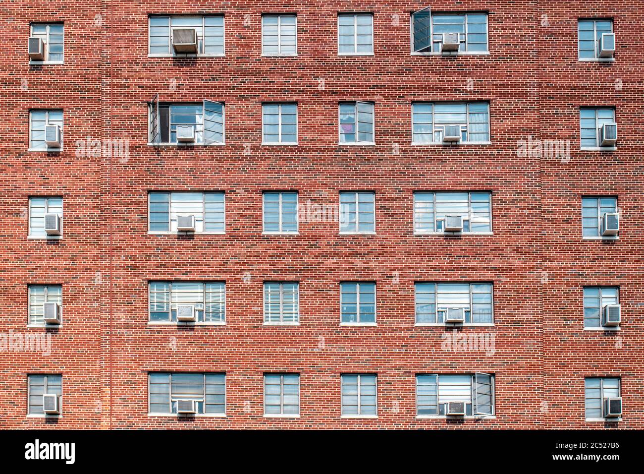 Immeuble d'appartements en brique rouge dans le centre-ville avec des fenêtres en verre bleu symétriques disposées dans un motif géométrique. Banque D'Images