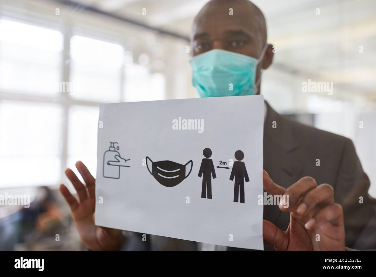 Homme d'affaires avec masque de visage en raison de Covid-19 fixe le tableau d'avis avec le concept d'hygiène de bureau Banque D'Images