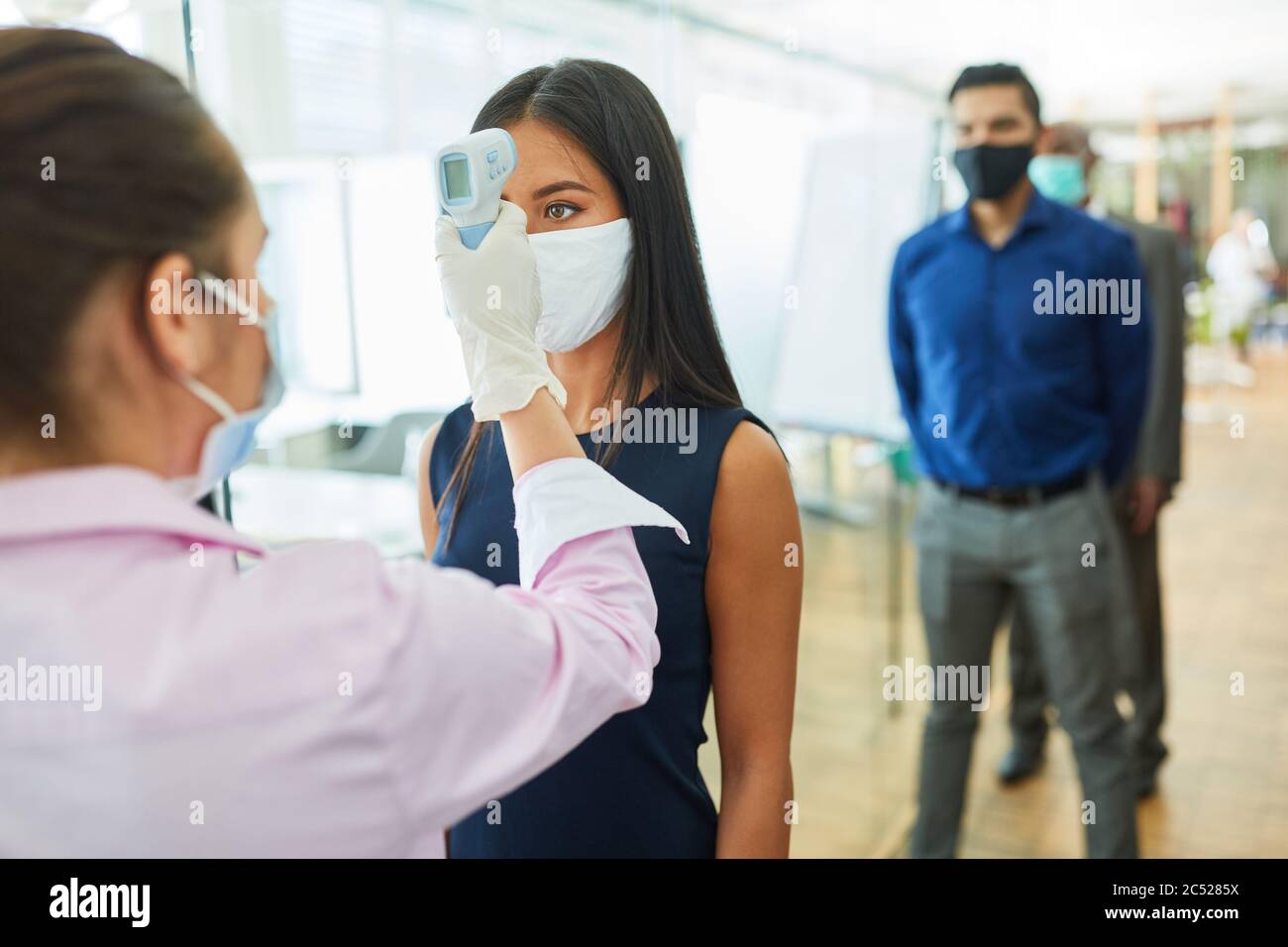 Les gens d'affaires avec la fièvre sans contact mesurent leurs fronts comme une prévention contre Covid-19 au bureau Banque D'Images