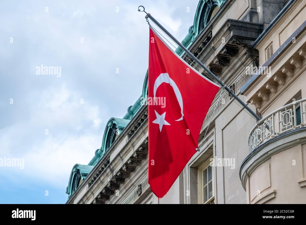 Drapeau dramatique de la Turquie vagues dans un ciel nuageux devant un bâtiment traditionnel. Banque D'Images