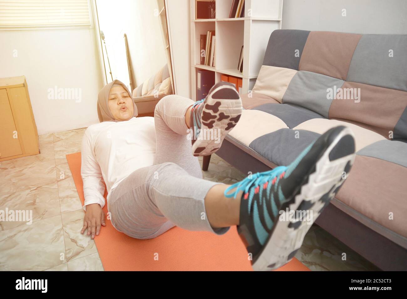 Femme musulmane asiatique portant le hijab faisant de l'exercice à la maison, garder en bonne santé et en forme pendant le nouveau style de vie normal, à l'intérieur de l'entraînement à la maison concept Banque D'Images