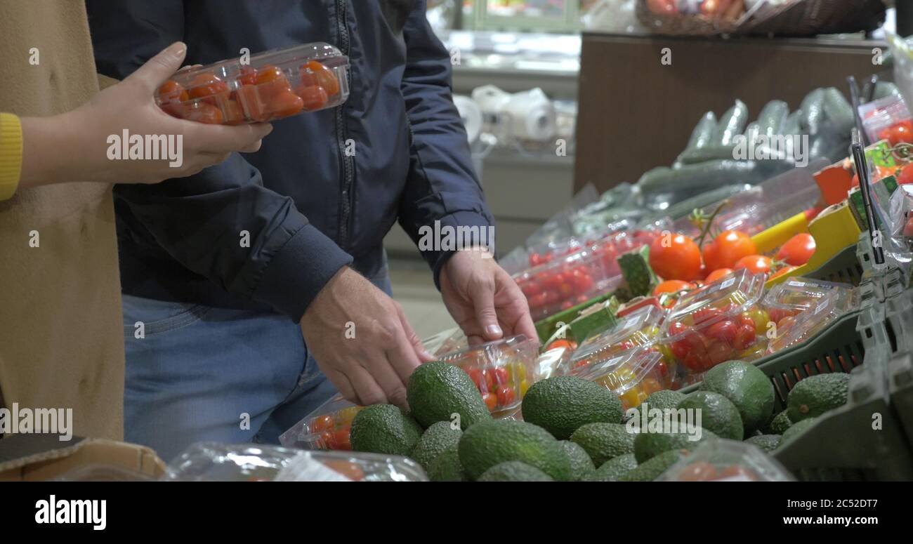 Clients choisissant des tomates au supermarché Banque D'Images