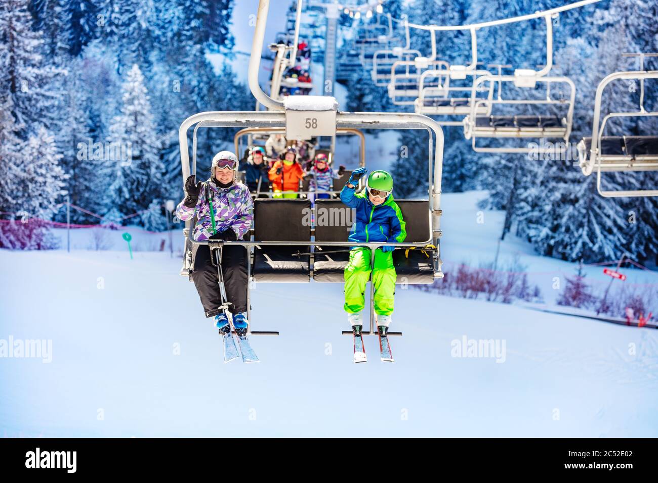 Un groupe d'enfants s'assoient sur un télésiège de la station de ski de montagne et se branle à la main Banque D'Images