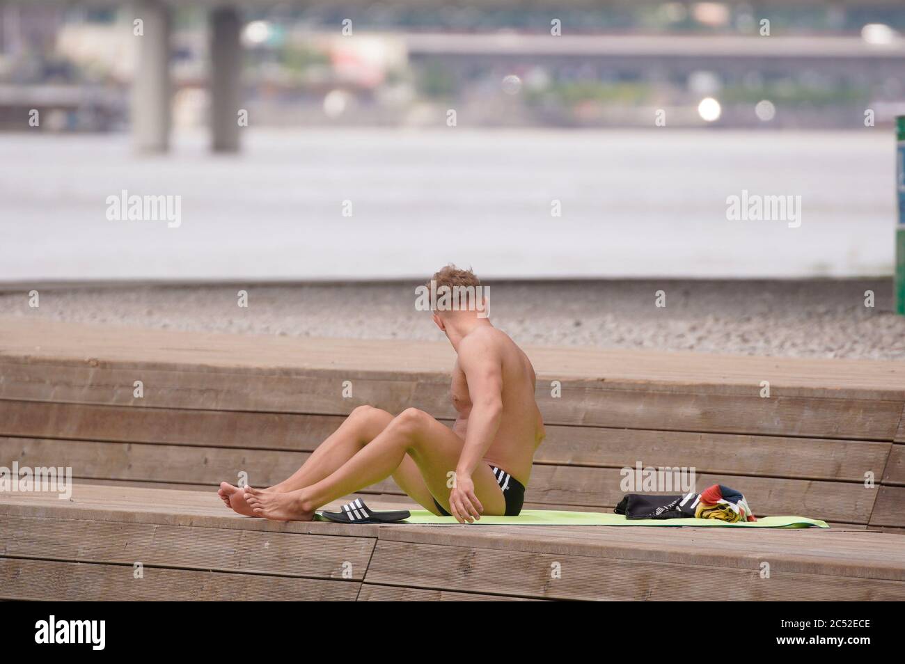 Un homme est vu bronzer près d'une plage partiellement inondée le 30 juin 2020 à Varsovie, Pologne. Pluies torrentielles et rafales de vent pouvant atteindre 100 kilomètres par heure Banque D'Images