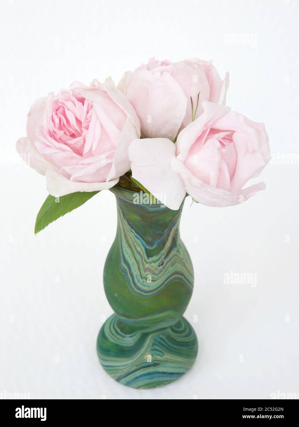 Trois roses roses délicates dans un vase vert malachite Banque D'Images