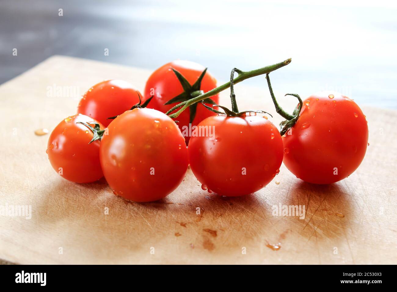 Tomates cerises fraîches sur une planche à découper en bois Banque D'Images
