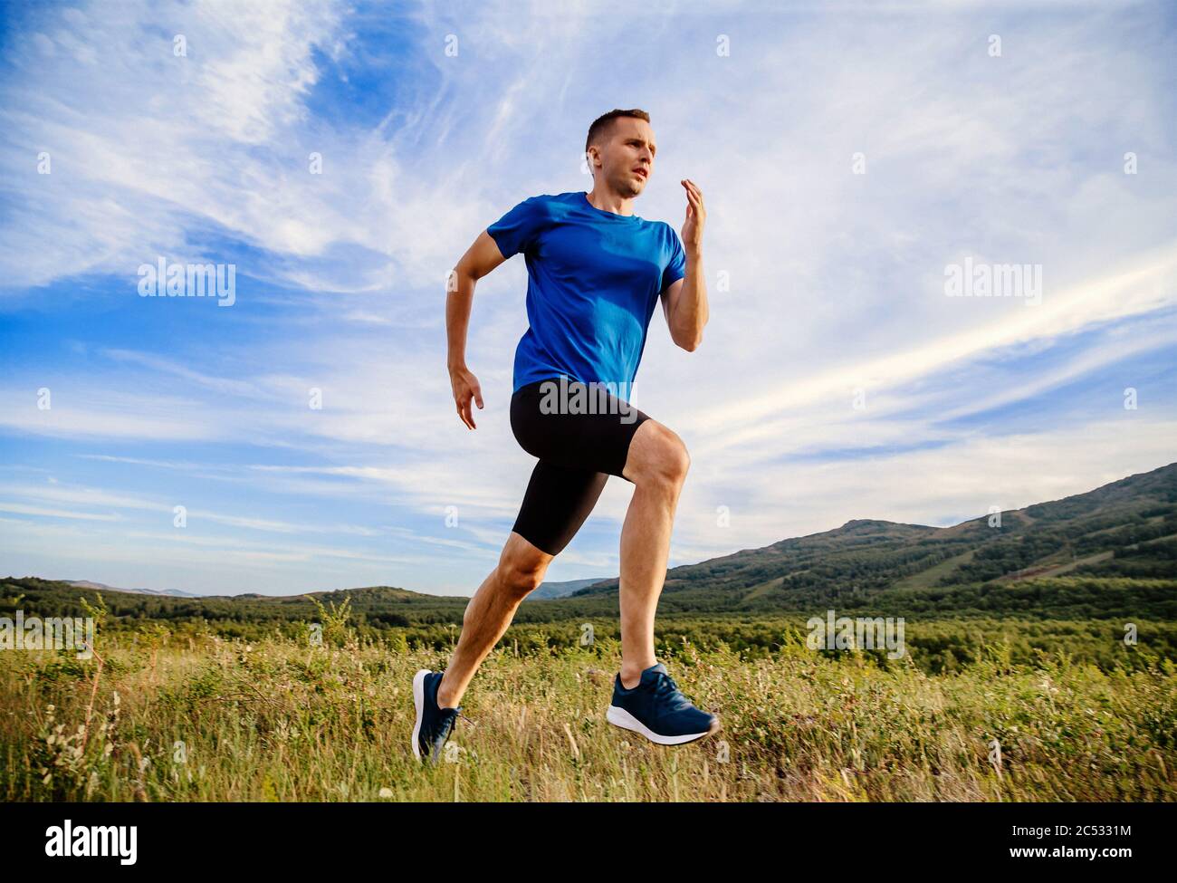 homme coureur courant été montagne prairie dans fond bleu ciel Banque D'Images