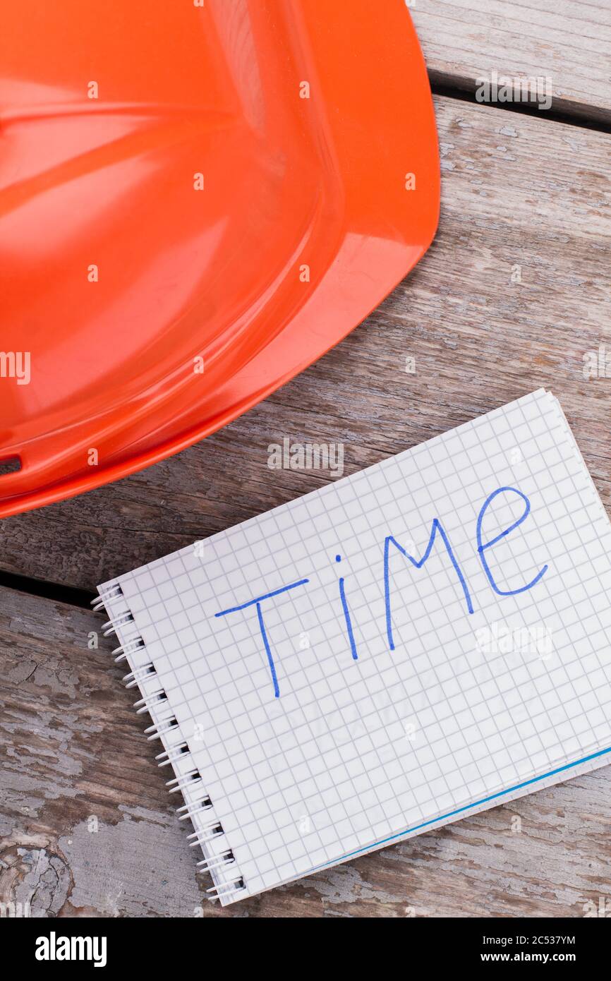 Casque et bloc-notes du travailleur du constructeur avec mot de temps. Banque D'Images