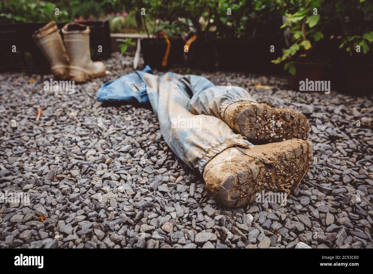 Paire différée de bottes de pumille sales avec de la boue après la journée dans la maternelle de forêt, en posant sur le sol avec une autre paire de bottes de pumbotte en arrière-plan Banque D'Images