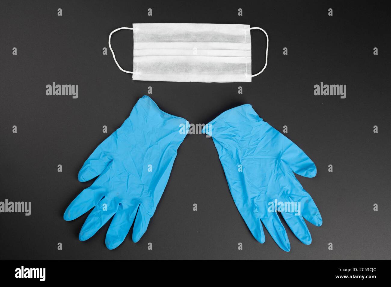 Masque de protection et gants médicaux en plastique bleu sur fond noir. Banque D'Images