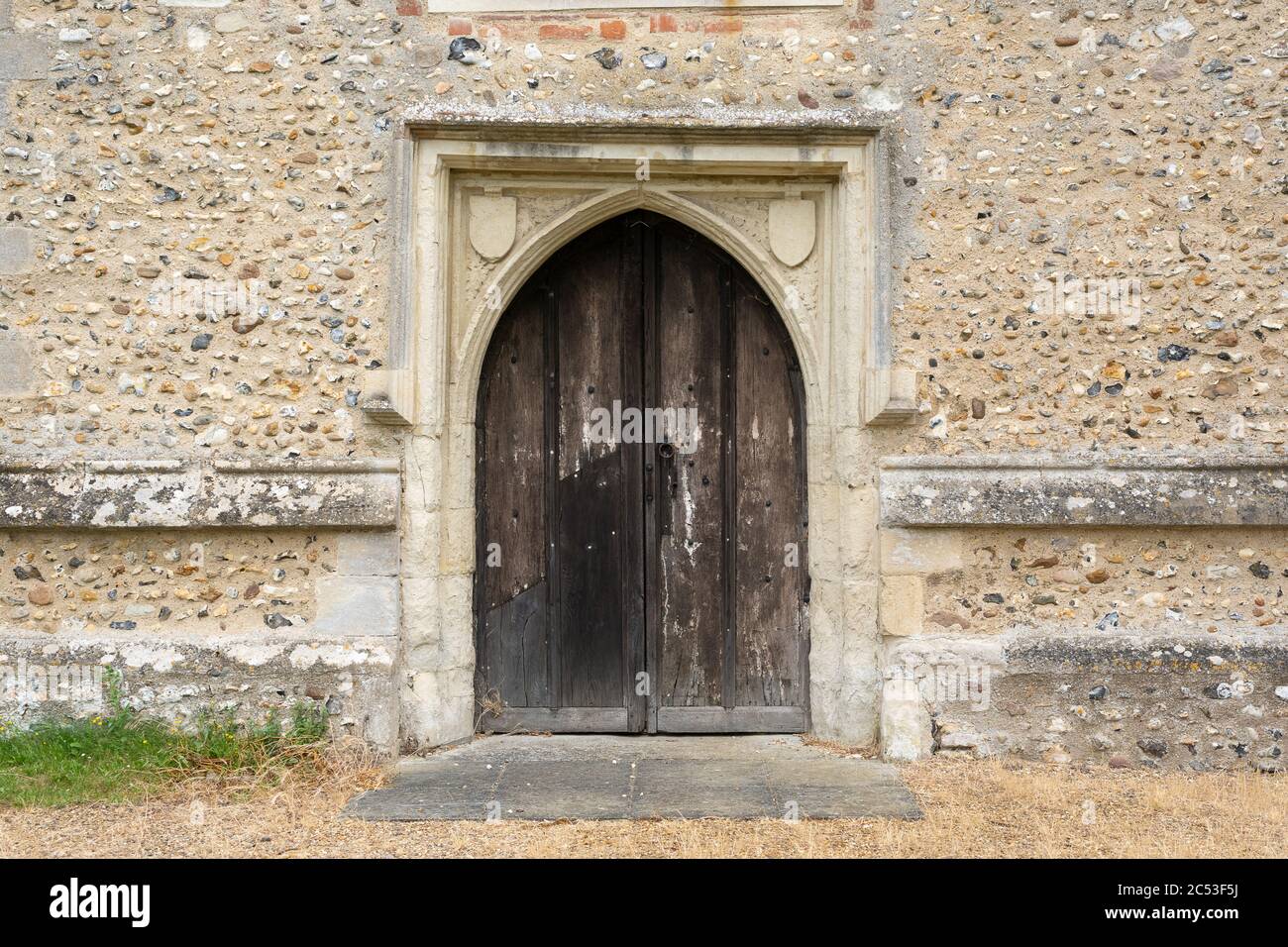 Très ancienne porte en bois voûté avec mur en pierre. Hunsdon, Hertfordshire. ROYAUME-UNI Banque D'Images