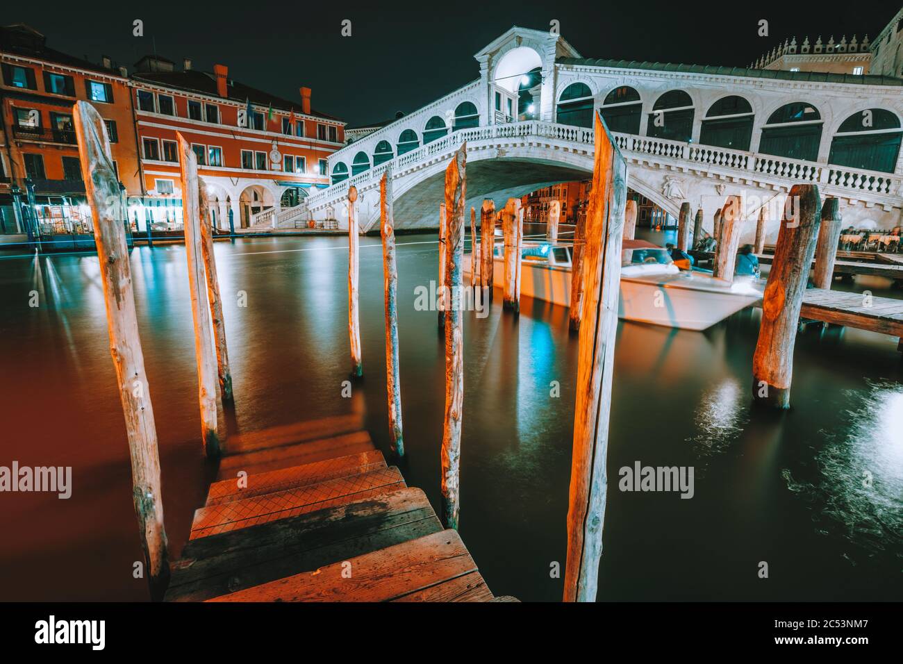 Venise, Italie. Vue nocturne sur la jetée du légendaire pont du Rialto, qui s'étend sur le Grand Canal éclairé par l'illumination de la ville. Banque D'Images