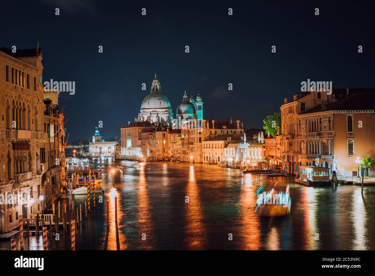 Venise, Italie. Grand Canal la nuit. Lumière d'éclairage réfléchie sur la surface de l'eau. Majestueuse basilique de Santa Maria della Salute en arrière-plan. Banque D'Images