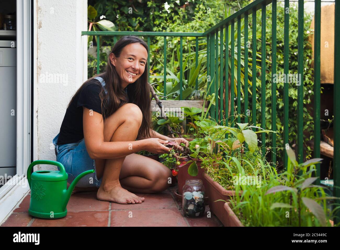 Jeune femme sur sa terrasse jardinage à la maison, concept de mode de vie naturel Banque D'Images