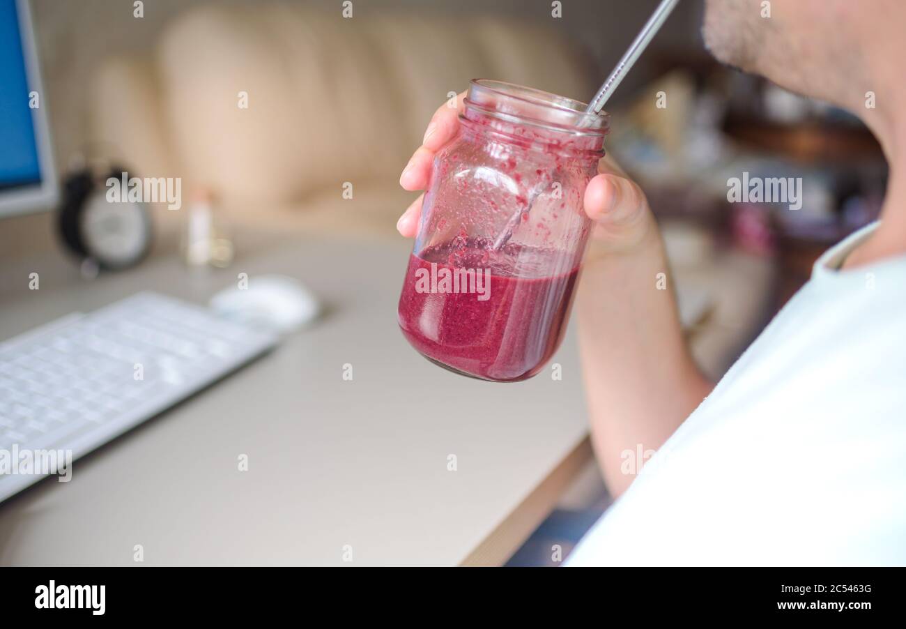 Indépendant travaillant sur l'ordinateur et buvant smoothie dans le bureau de création Banque D'Images