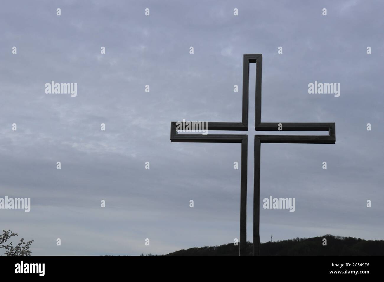 Une croix catholique en métal construite sur un parc commémoratif et un ciel nuageux en arrière-plan photographié d'en-dessous Banque D'Images