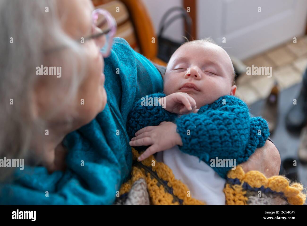 Cliché sélectif de petit garçon dormant dans les bras de sa grand-mère. Hors foyer, dans le coin supérieur gauche, les fiers yeux des aînés sur l'enfant Banque D'Images