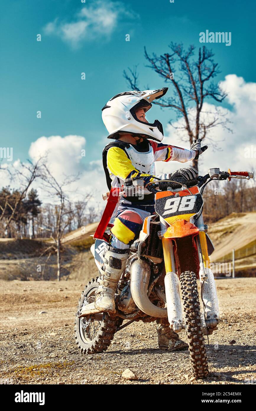 Portrait d'un garçon habillé et équipé pour les courses de moto assis sur  la moto Photo Stock - Alamy