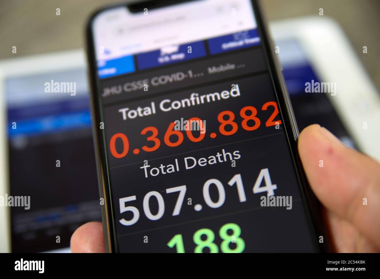 Viersen, Allemagne - juin 30. 2020: Gros plan de l'écran de téléphone portable tenir par main masculine avec le compteur de l'université John Hopkins montrant des nombres de worldwi Banque D'Images