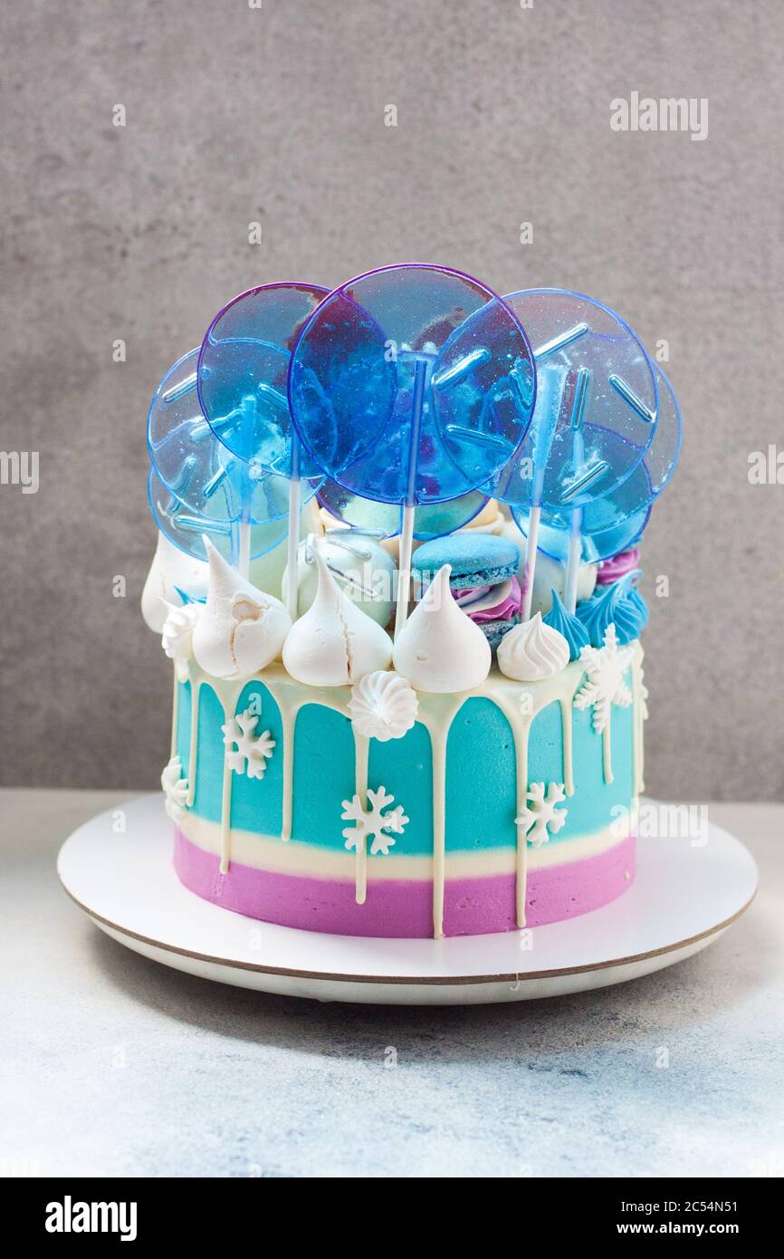 Gâteau d'hiver bleu au chocolat blanc, sucettes et flocons de neige fondants. Fond gris. Banque D'Images