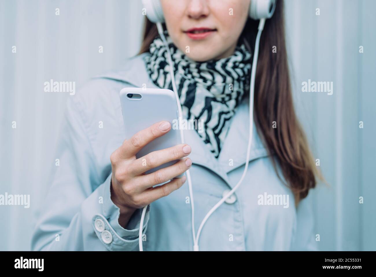 Une jeune fille dans un casque ou un manteau gris écoute un livre audio Banque D'Images