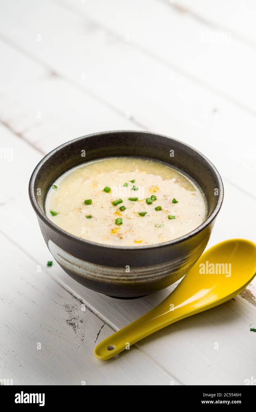 Soupe de maïs et cuillère jaune. Un plat de cuisine cantonaise souvent servi comme entrée dans les restaurants chinois. Le bol de soupe est sur fond blanc. Œuf Banque D'Images
