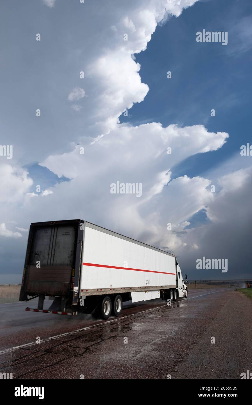 Camion roulant le long d'une autoroute rurale sur les hautes plaines après un orage passant avec des orages en arrière-plan Banque D'Images