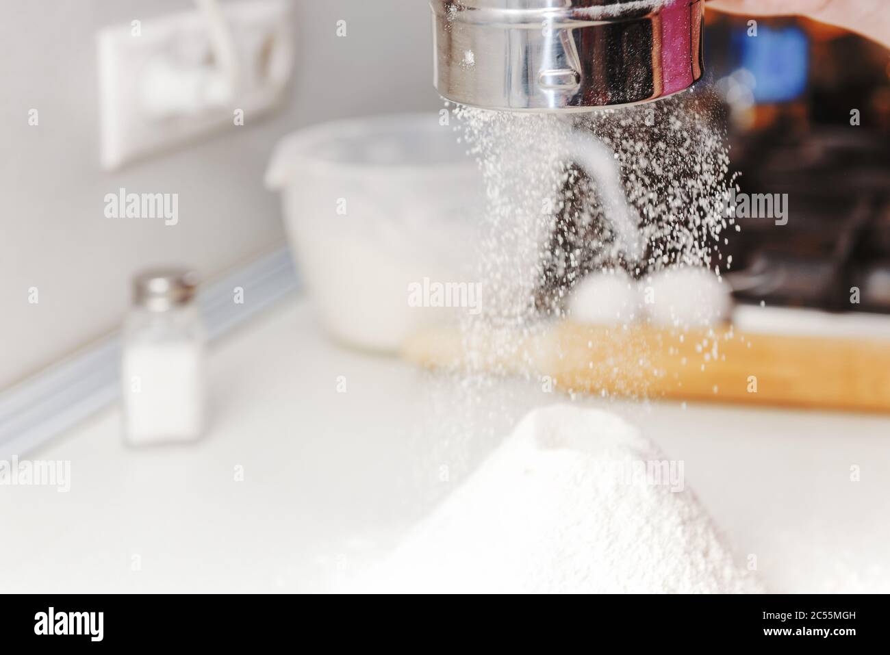 Les mains cuisent en gros plan. La main filtre la farine à travers le  tamis, la farine qui tombe est congelée. La farine se déplace sur la table.  Tamisez la farine. Baker