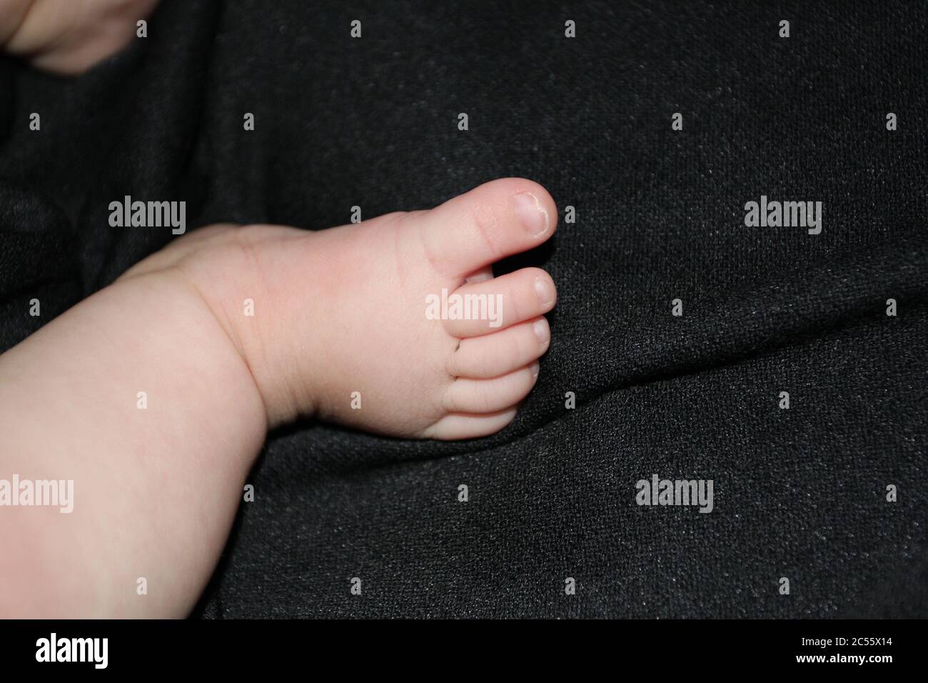 Pied de bébé de la petite fille sur fond noir. Banque D'Images