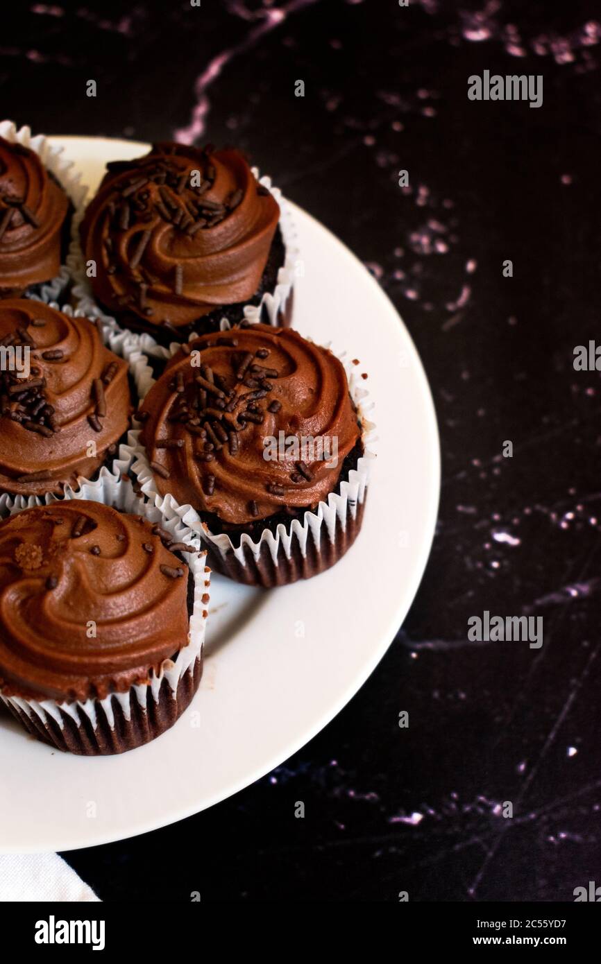 Cupcakes au chocolat sur une assiette blanche et fond noir marbré avec espace de copie. Faible profondeur de champ Banque D'Images