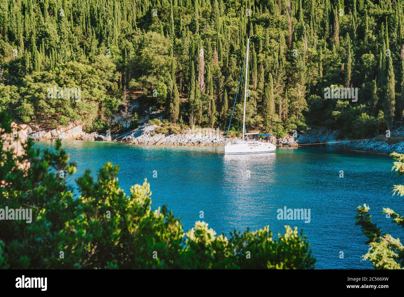 Bateau à voile yacht amarré dans la baie de Foki plage entourée de cyprès arbres, Fiskardo, Cefalonia, Ionienne, Grèce. Banque D'Images