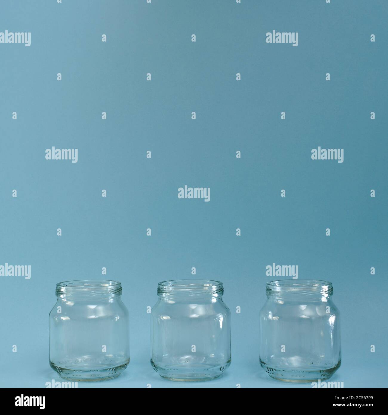 Rangée horizontale de trois bocaux transparents dans un carré bleu. Banque D'Images