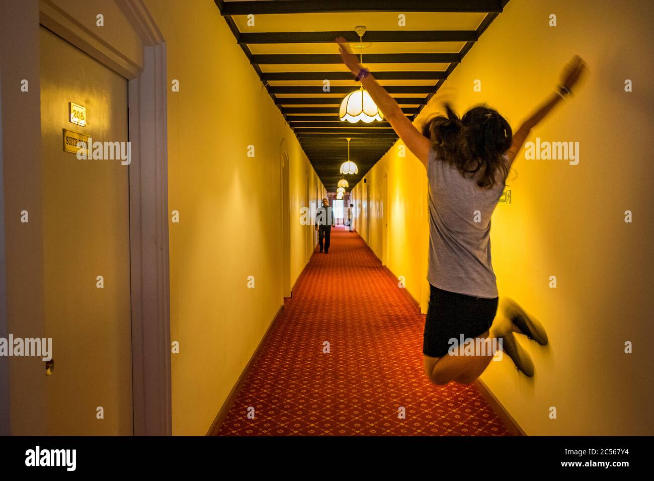 Une jeune femme qui saute dans les airs dans un couloir d'hôtel applaudissant Banque D'Images