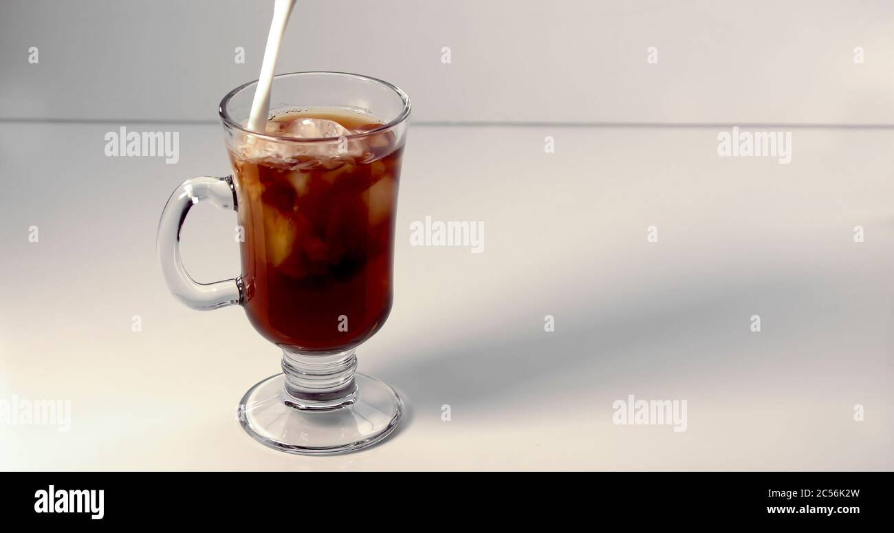 Verser de la crème sur une tasse de café glacé sur fond blanc Banque D'Images Verser de la crème sur une tasse de café glacé sur fond blanc Banque D'Images