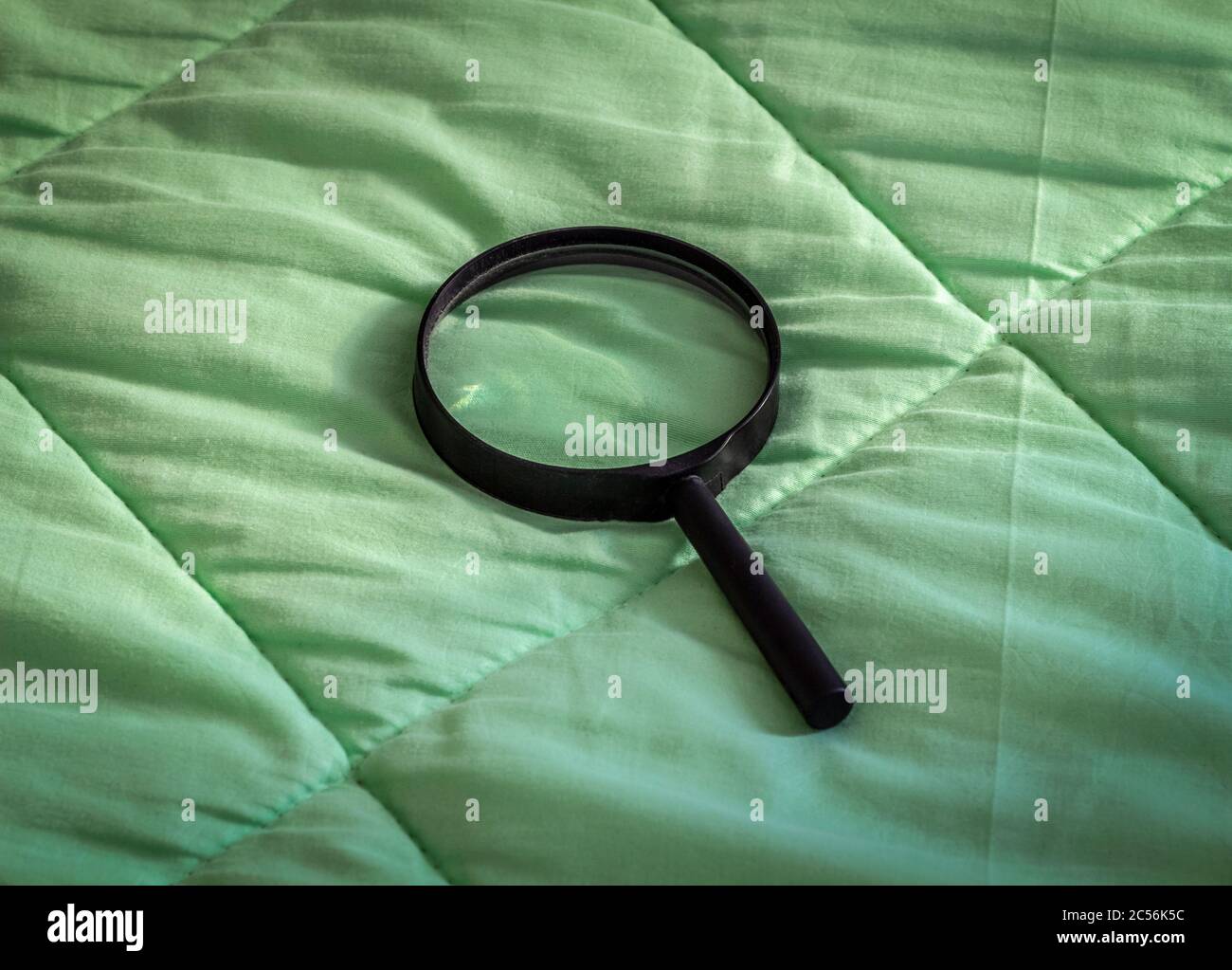 Une loupe noire repose sur une couverture verte. Banque D'Images