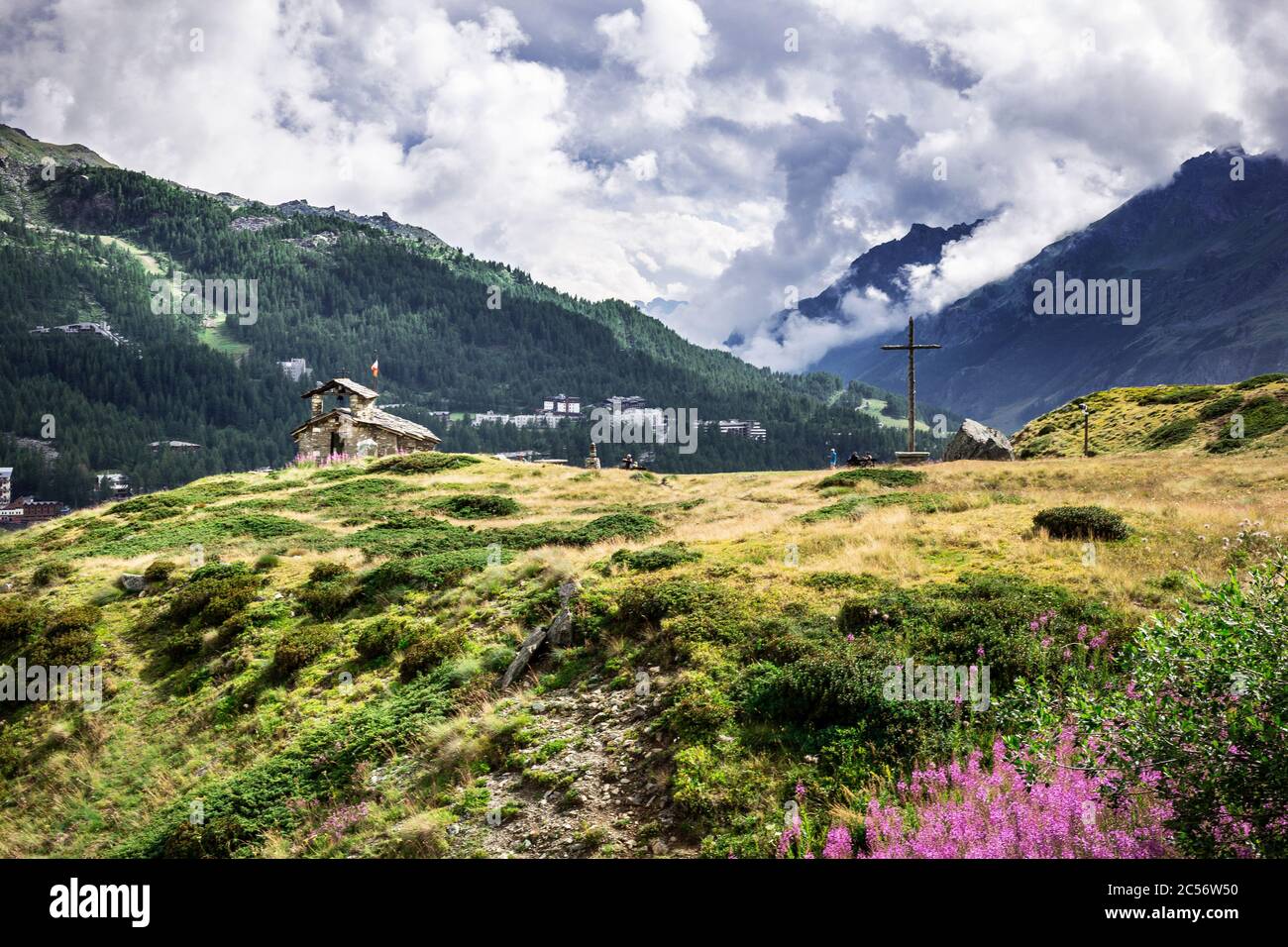 Vallée alpine de Breul Cervinia. Belle prairie avec fleurs. Petite église et croix sur le fond. Église de l'Alpini. Banque D'Images