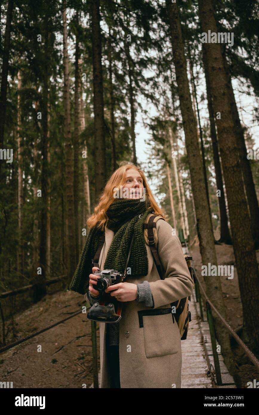 Femme REDHEAD avec caméra sur la passerelle dans les bois Banque D'Images