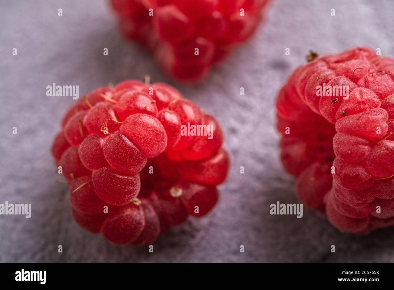 Fruits frais mûrs de framboise, vitamine d'été fruits rouges de baie sur fond de béton de pierre, vue d'angle macro Banque D'Images