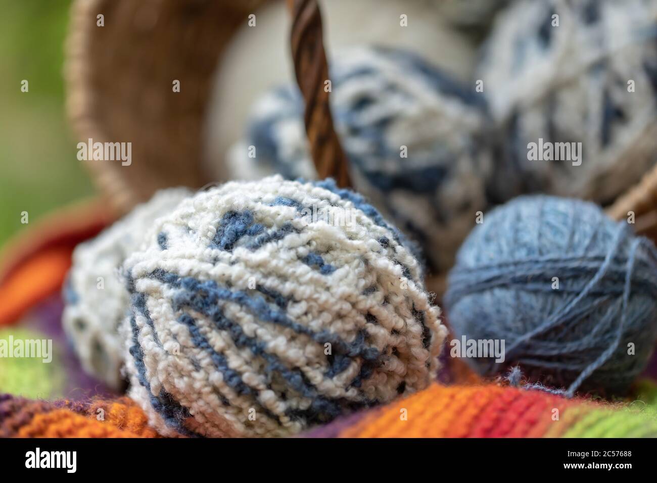 Gros plan de boules de laine blanche-bleue moelleuses dans un panier sur fond naturel. Fils pour tricoter. Articles pour les travaux d'aiguille féminins. Banque D'Images